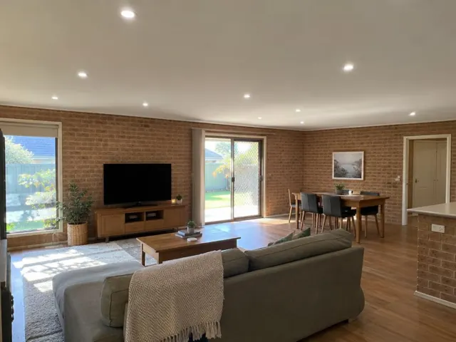 Living room with multiple recessed downlights in a brick-walled home in Woongarrah